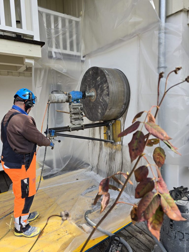Mitarbeiter führt eine runde Kernbohrung für eine Fensteröffnung durch