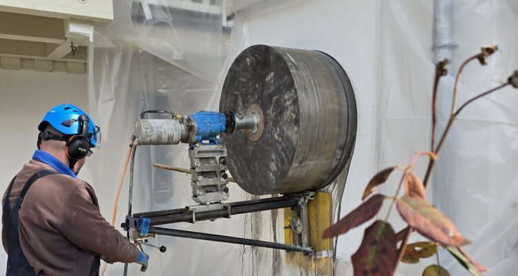 Mitarbeiter führt eine runde Kernbohrung für eine Fensteröffnung durch