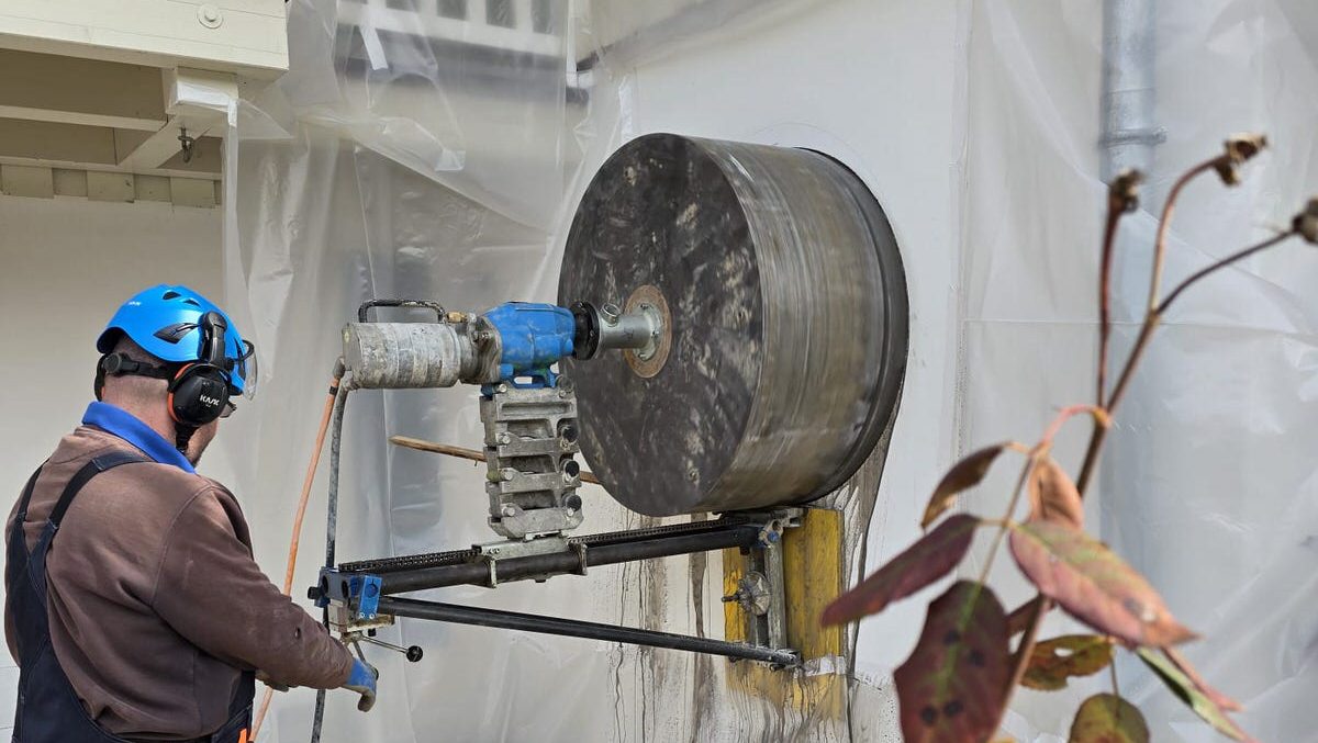 Mitarbeiter führt eine runde Kernbohrung für eine Fensteröffnung durch